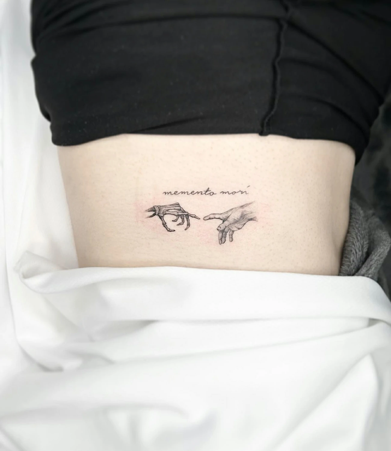 minimalist memento mori tattoo: A simple, clean design of "memento mori" with minimal detail, focusing on sleek lines and basic shapes.